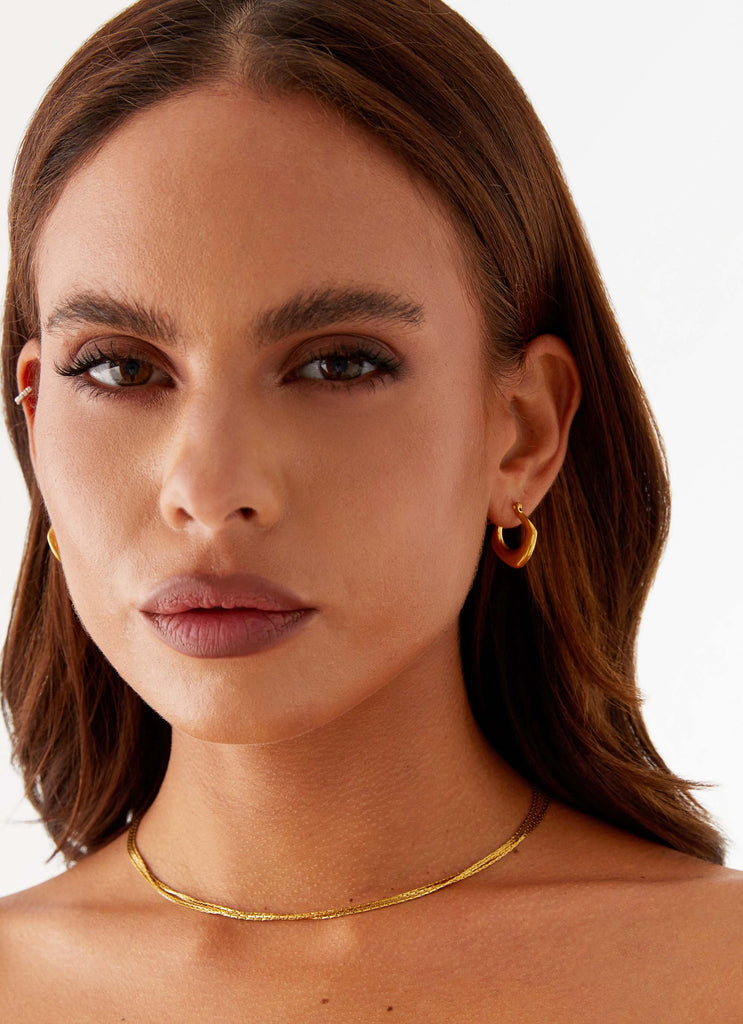 Womens High Voltage Earrings in the colour Gold in front of a light grey background