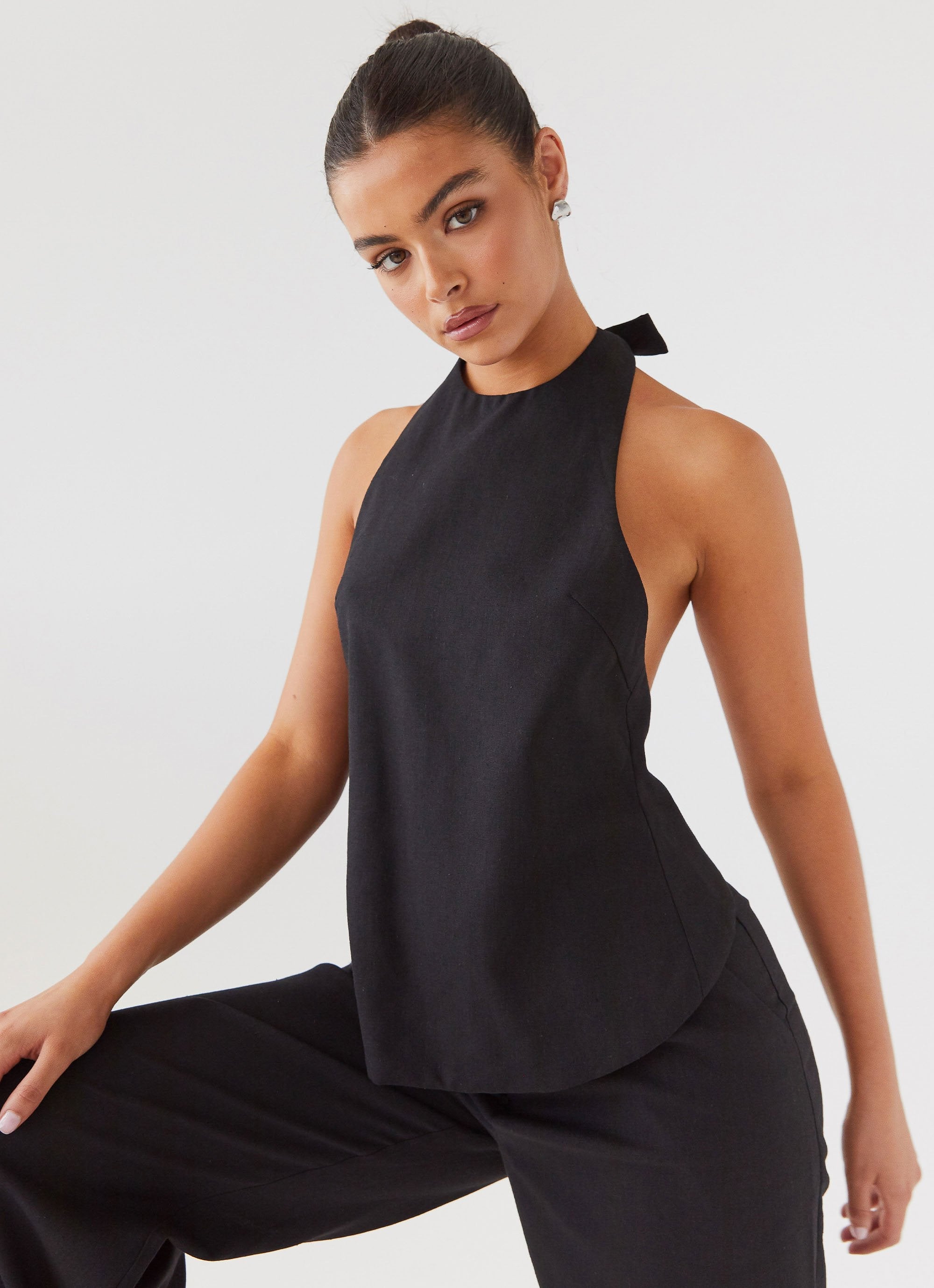 A black linen apron top draped over a wooden surface, highlighting its relaxed drape and natural drape